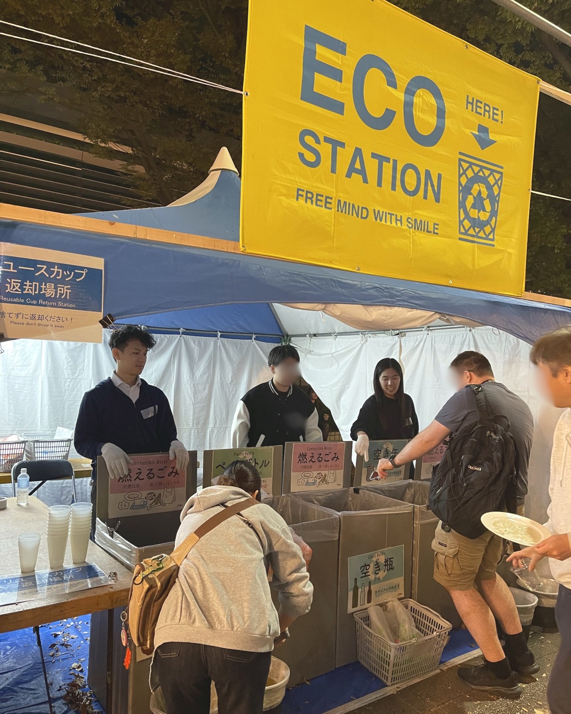 黄色い「ECO STATION」の看板の下で、エコステーションを担当するUr AIのメンバー
